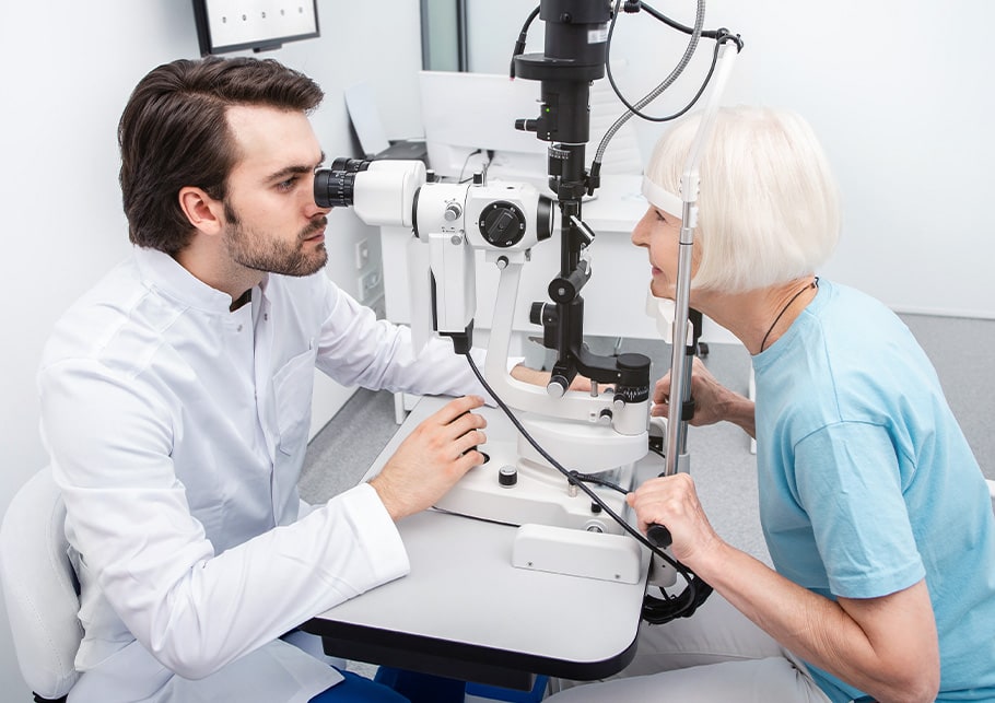 A male optometrist examines an older female patient's eyes for certain diseases related to her eyes