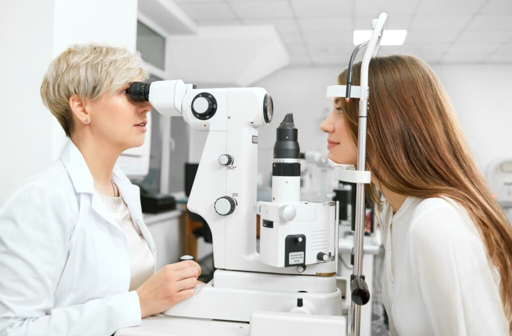 An optometrist conducts an eye exam on a smiling patient.