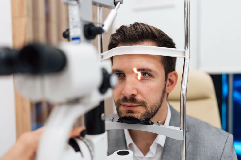 An adult is at an eye assessment machine during his eye exam.