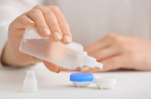 Hand pouring contact lens solution into a lens case.