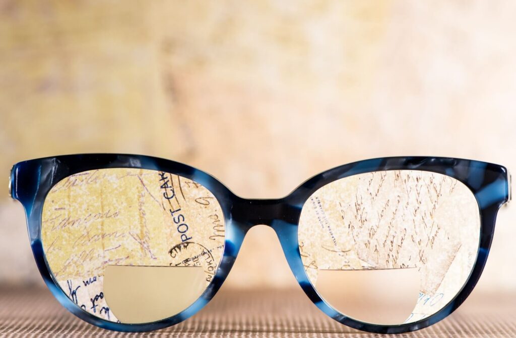 A pair of bifocal eyeglasses resting in front of handwritten notes, showing the difference between the distant and near focal points.