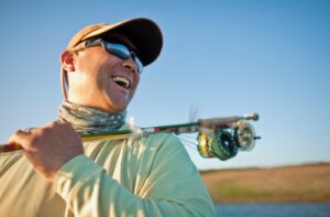 A smiling angler wearing polarized sunglasses to protect their eyes while fishing.