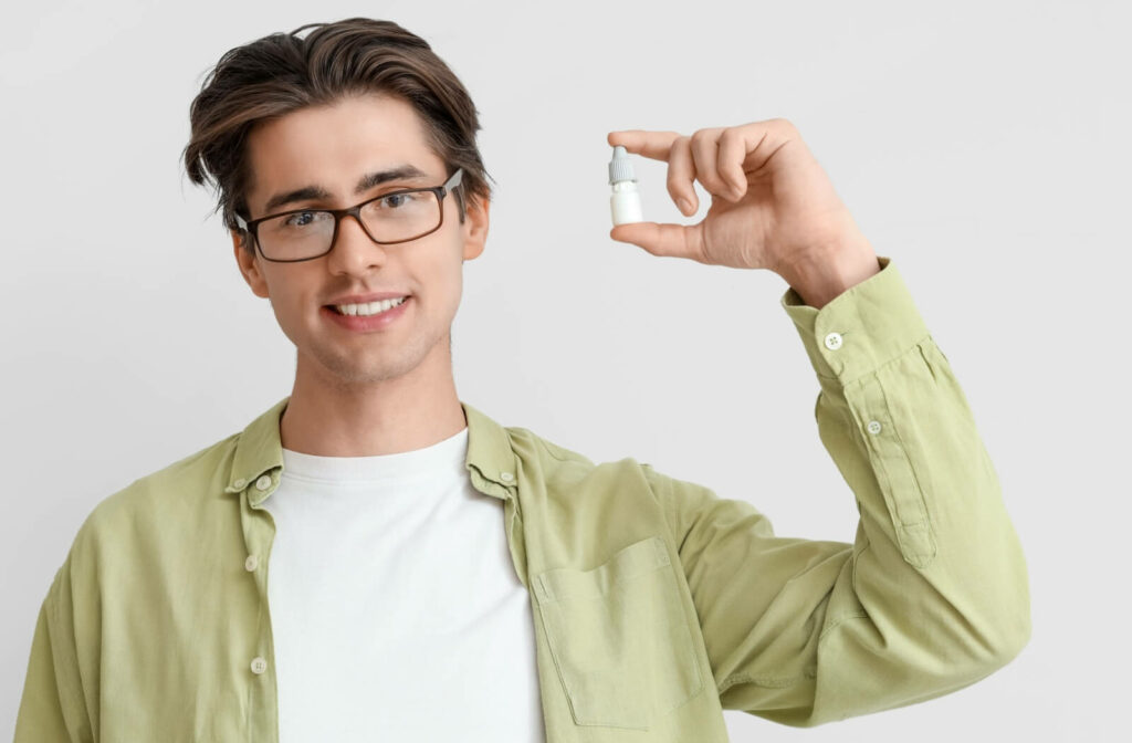 A person holds up a bottle of eye drops.