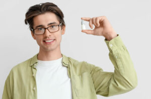 A person holds up a bottle of eye drops.