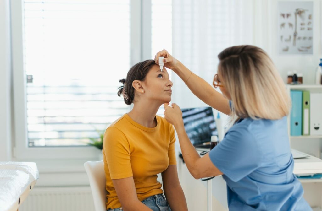 An optometrist carefully administers a patient's eye drops while explaining safe handling.