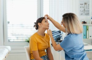 An optometrist carefully administers a patient's eye drops while explaining safe handling.
