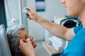 An optometrist administers dilating eye drops to a patient during their exam.